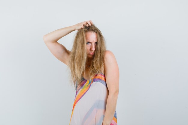 Young lady in summer dress posing with hand on head and looking confident 