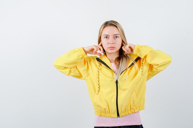 Tシャツを着た若い女性、指で耳を塞いでイライラしているジャケット