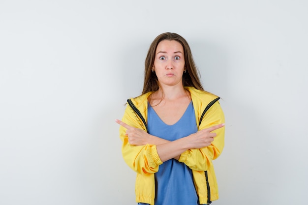 Young lady in t-shirt, jacket pointing to the both sides and looking hesitant , front view.