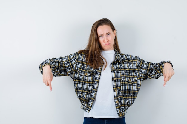 Free photo young lady in t-shirt, jacket pointing down and looking cheerless , front view.