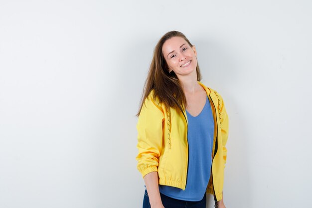 Young lady in t-shirt, jacket posing while standing and looking cute, front view.