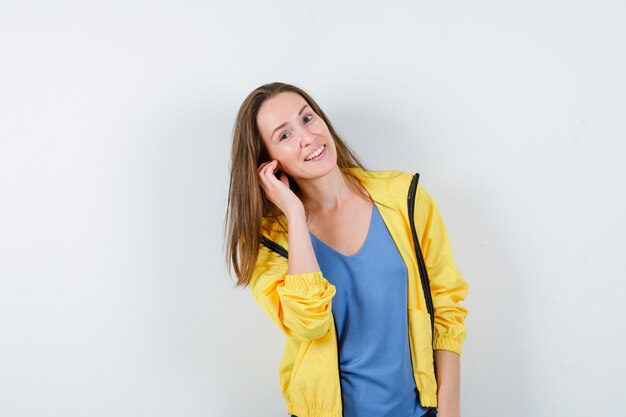 Young lady in t-shirt, jacket posing while standing and looking delightful, front view.