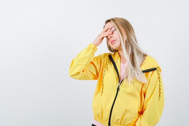 Young lady in t-shirt, jacket rubbing her eyes and looking sleepy