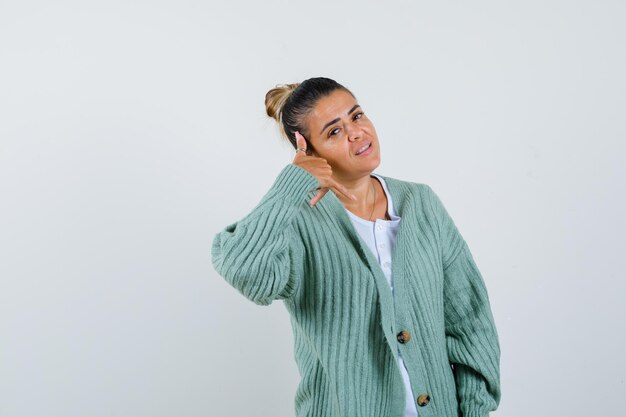 Young lady in t-shirt, jacket showing call me gesture and looking confident