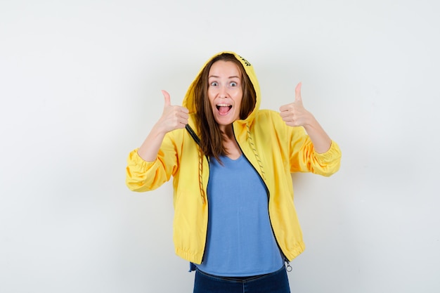 Young lady in t-shirt, jacket showing double thumbs up and looking happy , front view.