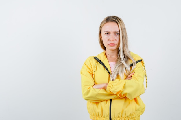 Young lady in t-shirt, jacket standing with crossed arms and looking confident