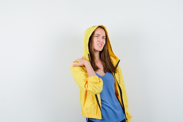 Young lady in t-shirt, jacket suffering from shoulder pain and looking uncomfortable , front view.