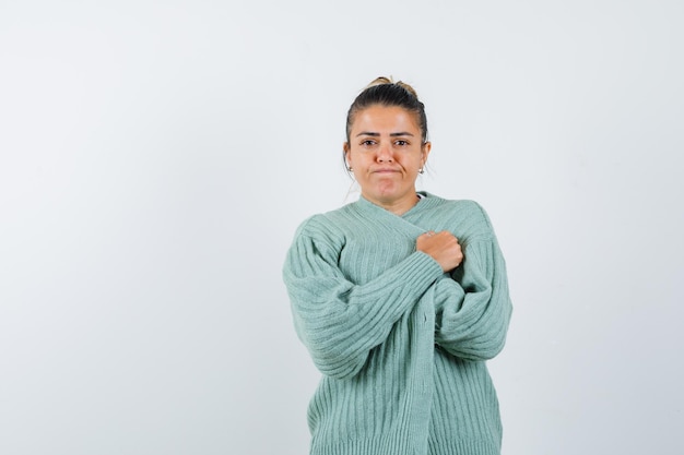 Young lady in t-shirt, jacket wrapping jacket and looking wistful