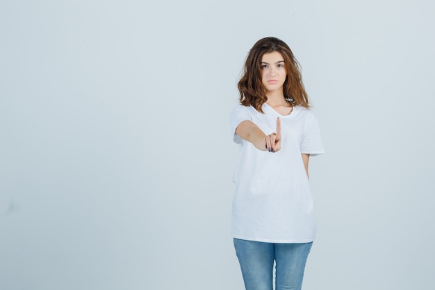 Young lady in t-shirt, jeans hold on a minute and looking confident , front view.