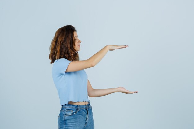 Young lady in t-shirt , jeans showing large size sign and looking fortunate , front view.