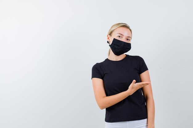 Young lady in t-shirt, pants, medical mask welcoming something isolated