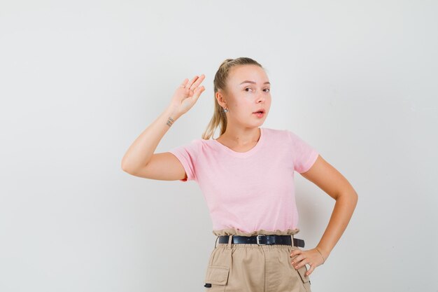 Young lady in t-shirt and pants showing ok gesture and looking confident