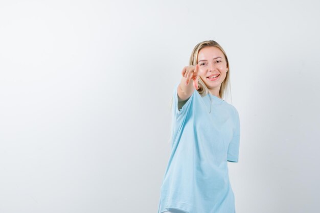 Young lady in t-shirt pointing at camera and looking happy isolated