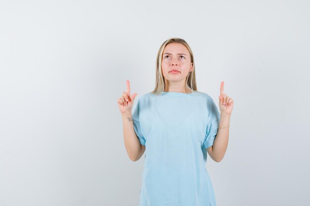 Young lady in t-shirt pointing up and looking hesitant isolated