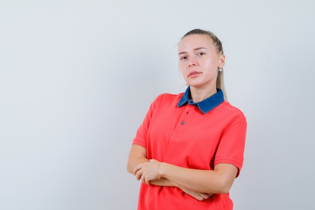 Young lady in t-shirt posing while standing and looking confident