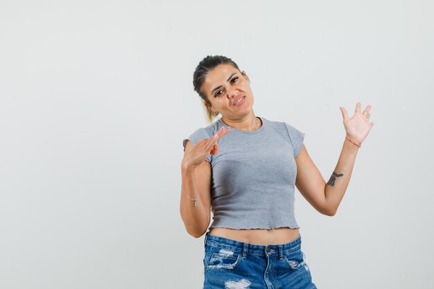 Young lady in t-shirt, shorts showing palm with ok sign and looking confident