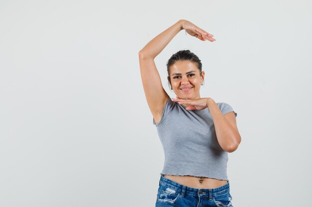 Tシャツを着た若い女性、伝統的なダンスのジェスチャーを示し、陽気に見えるショートパンツ