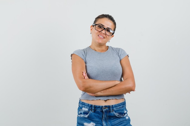 Young lady in t-shirt, shorts standing with crossed arms and looking confident