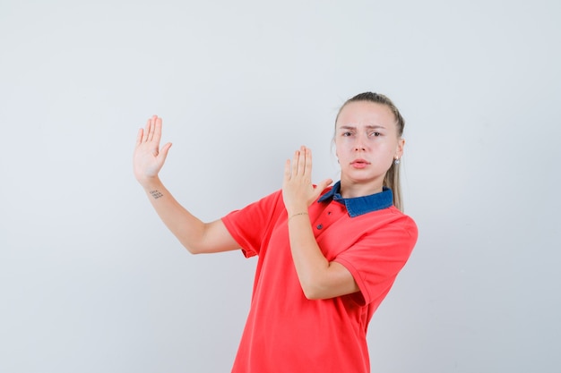 空手チョップジェスチャーを示し、厳格に見えるTシャツの若い女性