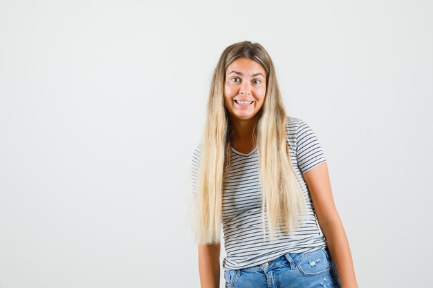 Young lady in t-shirt standing while smiling and looking cheery , front view.