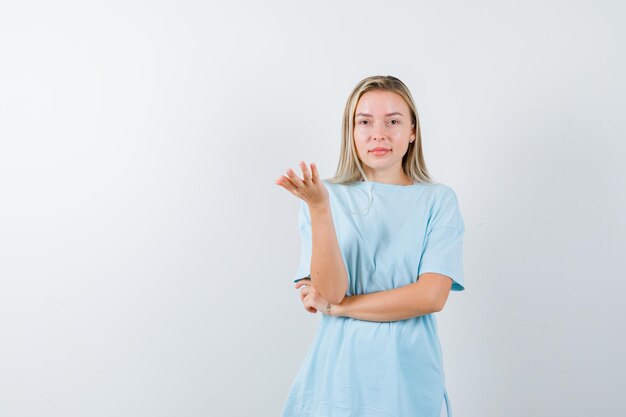 Young lady in t-shirt stretching hand in questioning gesture and looking pretty isolated