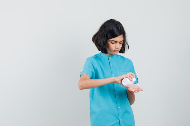 Молодая дама принимает таблетки из бутылки в синей рубашке