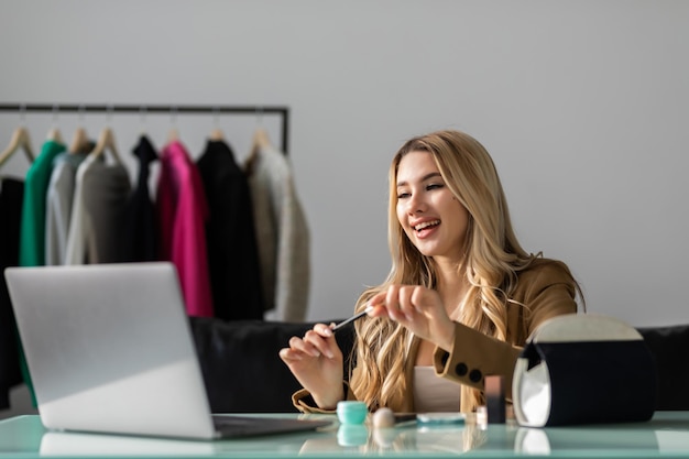 Foto gratuita giovane donna che parla di cosmetici in possesso di una tavolozza di trucco mentre registra il suo video donna che fa un video per il suo blog sui cosmetici