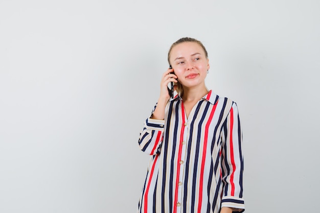 Young lady talking on mobile phone in striped shirt and looking cheery