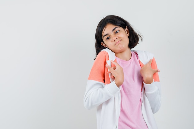 Young lady touching her collar in jacket, pink shirt and looking confused