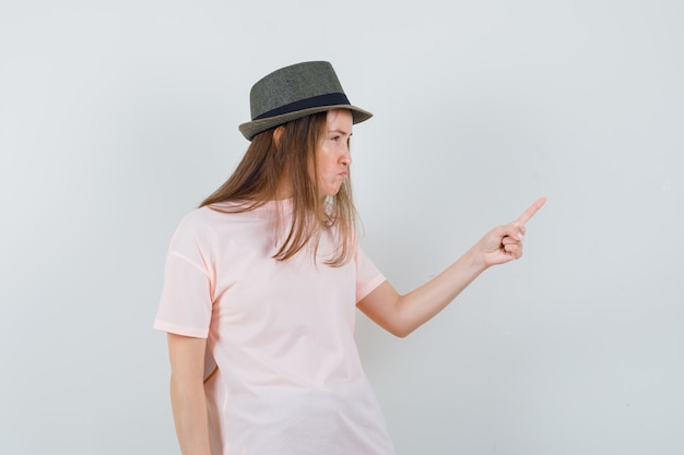 Young lady warning with finger in pink t-shirt hat and looking spiteful 