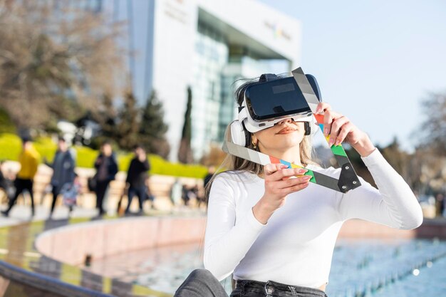 Барышня носит комплект виртуальной реальности и сидит на улице