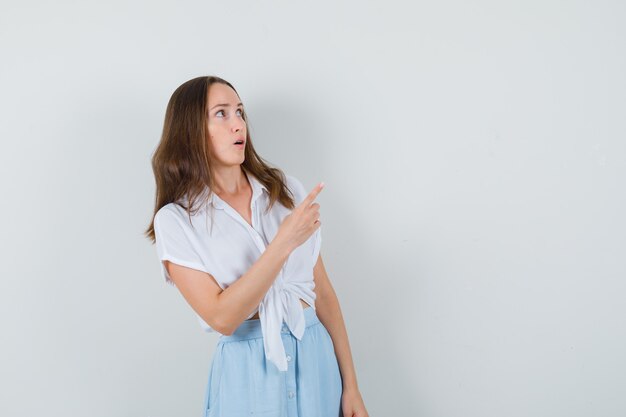 Девушка в белой блузке, синяя юбка, указывающая вверх слева и обеспокоенная