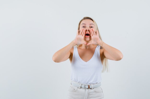 Young lady in white blouse calling someone with loud voice and looking focused