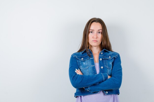 Young lady with arms folded in t-shirt, jacket and looking serious , front view.