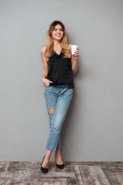 Young lady with cup of coffee posing isolated