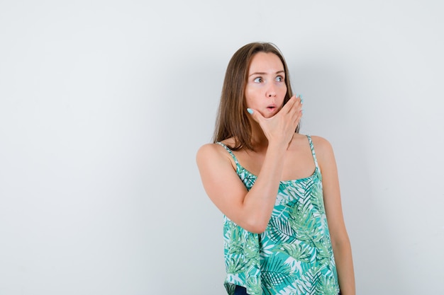 Young lady with hand on chin, looking away and looking wondered. front view.