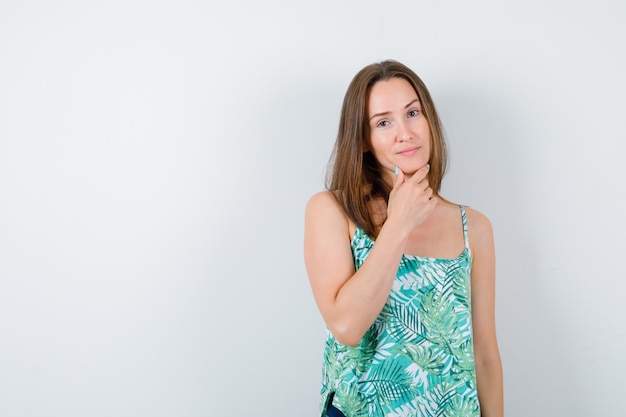 Young lady with hand on chin and looking confident , front view.