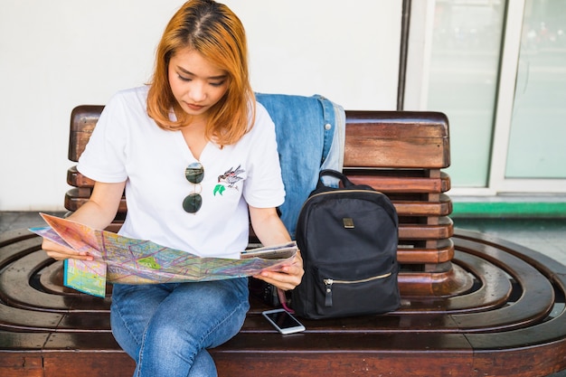 Young lady with map on bench 