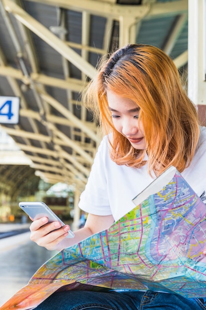 Young lady with smartphone and map