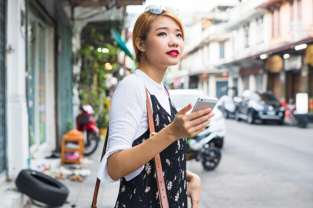 ストリートにスマートフォンを持つ若い女性