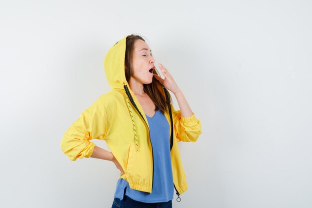 Young lady yawning in t-shirt, jacket and looking sleepy