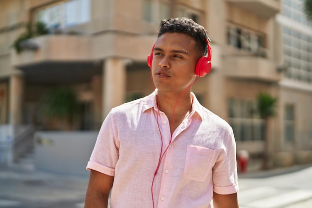 Young latin man listening to music at street