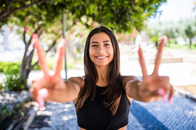 Foto gratuita giovane donna latina con gesto di pace in piedi su una strada.