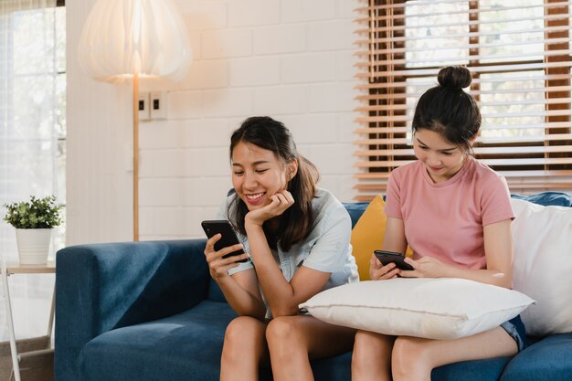 Young Lesbian lgbtq women couple using mobile phone at home