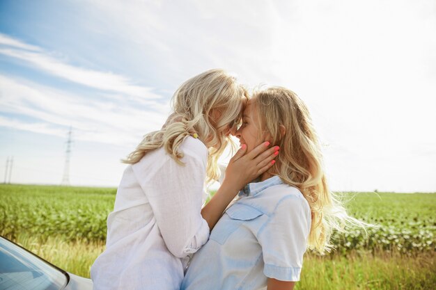 The young lesbian's couple broke down the car while traveling on the way to rest. Kissing and cuddling on the car's trunk. Relationship, troubles on the road, vacation, holidays, honeymoon concept.