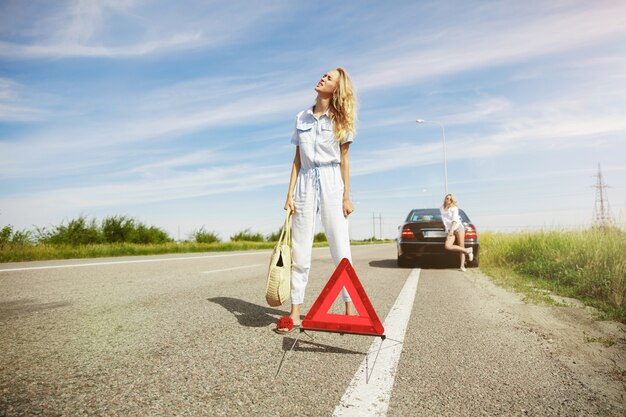 Young lesbian's couple going to vacation trip on the car in sunny day