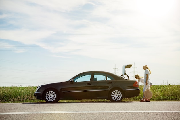 Young lesbian's couple going to vacation trip on the car in sunny day