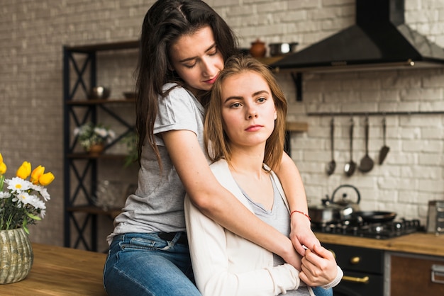 Young lesbian woman loving her girlfriend standing in the kitchen