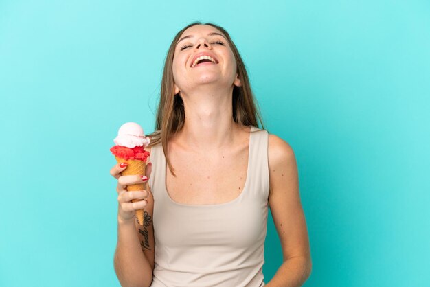 Молодая литовская женщина с мороженым корнет, изолированные на синем фоне смеясь