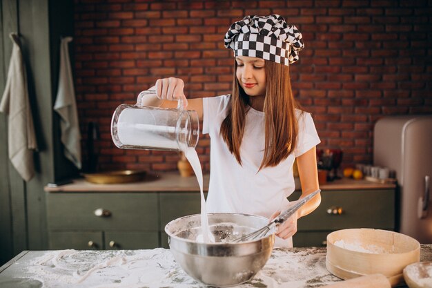 Young little girl baking pastry at the kitchen for breakfast